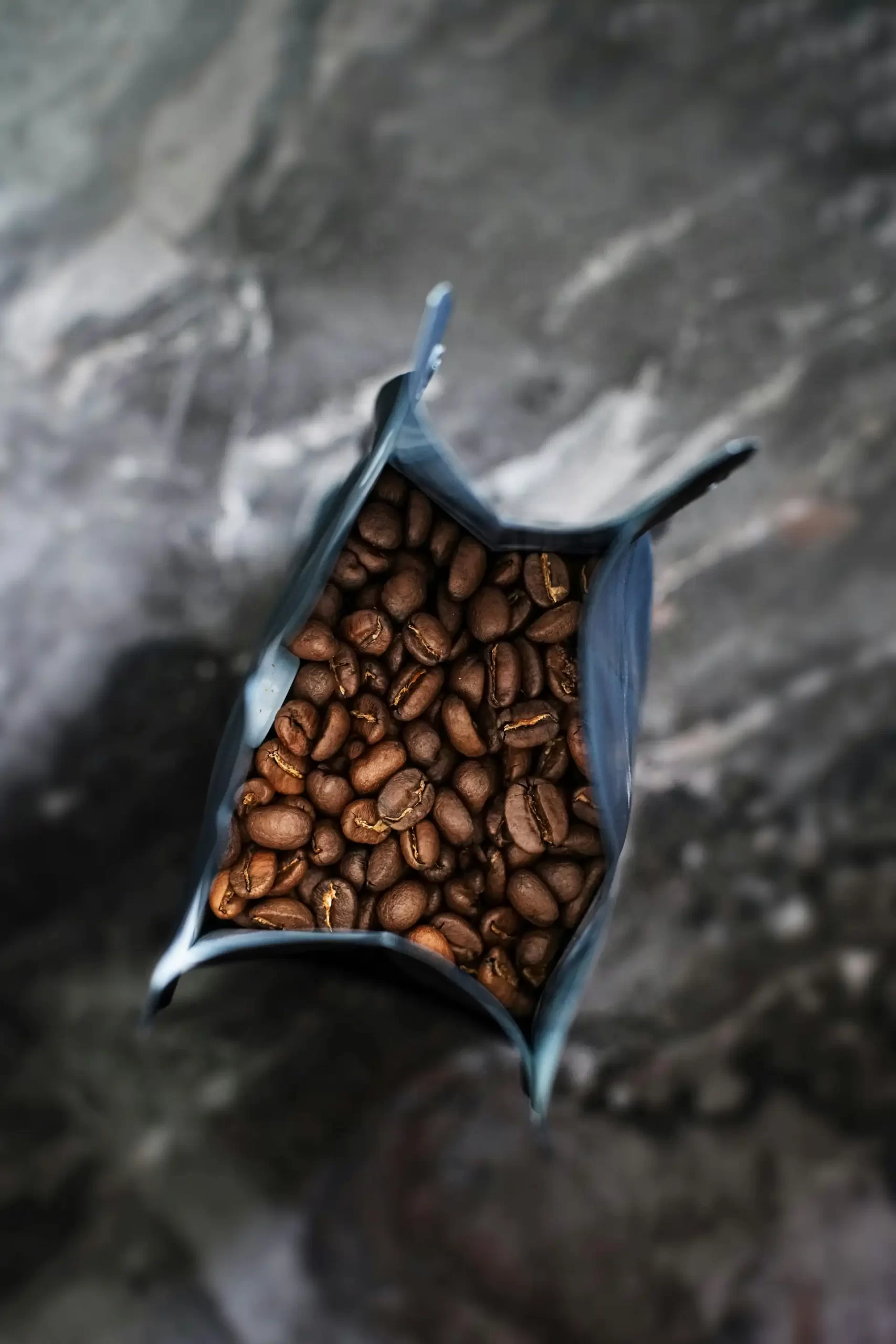This image provides a top-down, interior view of a dark coffee bag filled with roasted beans.